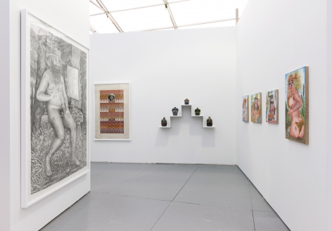 Installation view of an art fair booth. Sculptures and paintings are on the walls