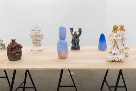 An installation view of the group exhibition "Morph". There are many sculptures on a table in the gallery