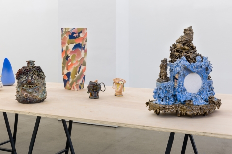 An installation view of the group exhibition "Morph". There are many sculptures on a table in the gallery