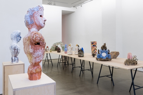 An installation view of the group exhibition "Morph". There are many sculptures on a table in the gallery. Busts are on pedestals
