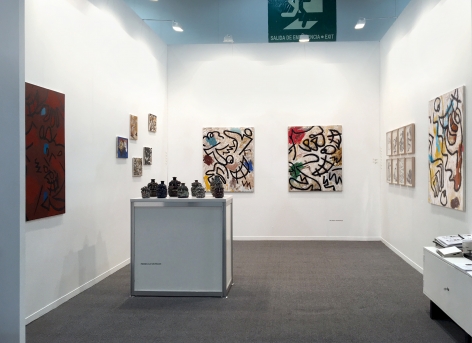 Installation view of the art fair booth at Zona Maco. Paintings are on the walls and sculptures are on a table