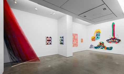 Installation view of "Adriadne Unraveling". Large sculptural installation in left corner, with textile works on the wall.